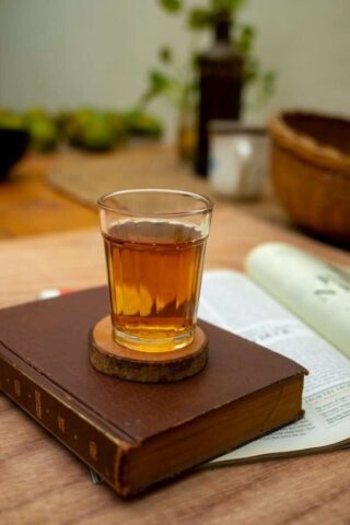 A warm glass of tea rests on an old book, creating a cozy and inviting atmosphere.