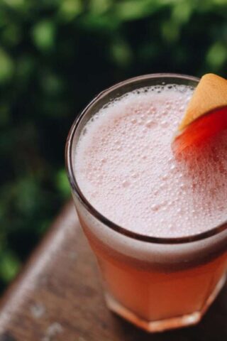 Photo by Cocodillaa.com Top-down view of a frothy grapefruit drink with citrus slice. Ideal for summer refreshment.