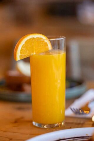 Photo by Cocodillaa.com A vibrant glass of orange juice with a fresh orange slice for a healthy refreshment.