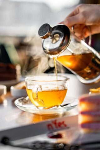 Warm tea being poured into a glass cup from a French press outdoors in Ünye, Türkiye.