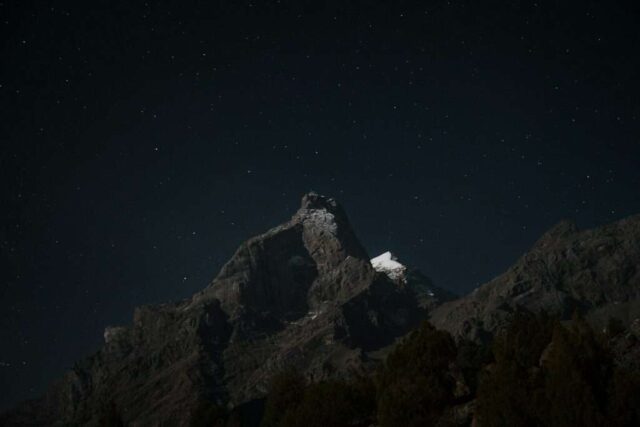 The night sky with stars above a mountain