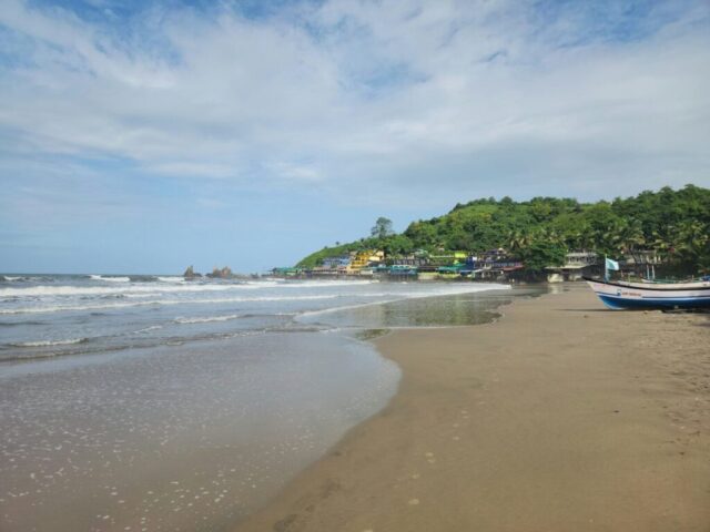 A beach with a boat on the sand and trees in the background