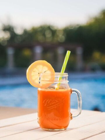 Photo by Cocodillaa.com Delicious orange juice in a mason jar with lemon slice by the pool for a refreshing summer drink.
