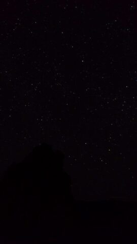 the night sky with stars above a mountain