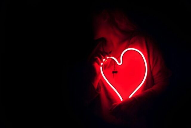 Photo by Cocodillaa.com a heart shaped neon sign in the dark