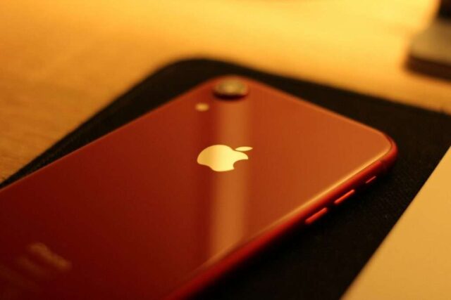 A red iPhone sitting on top of a wooden table
