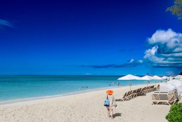A person walking on a beach with chairs and umbrellas