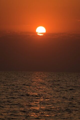 Photo by Cocodillaa.com the sun is setting over the ocean on a cloudy day