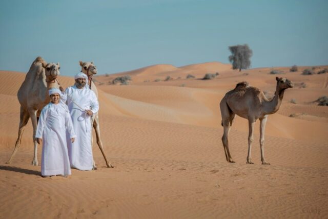 Photo by Cocodillaa.com woman in white dress standing beside camel on desert during daytime