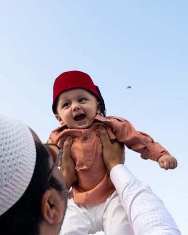 Photo by Cocodillaa.com Father holds happy baby wearing a red fez hat