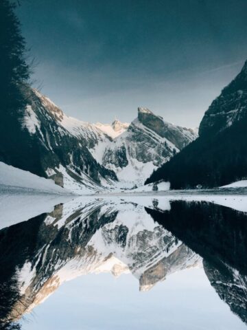 Photo by Cocodillaa.com snow-covered mountain near lake under blue sky