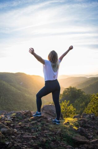 Photo by Cocodillaa.com woman in white shirt and black pants standing on rocky mountain during daytime