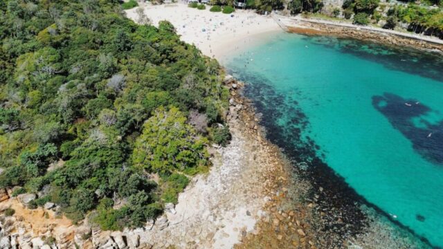 an aerial view of a sandy beach with clear blue water