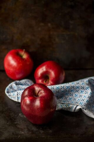 three red apples on brown surface