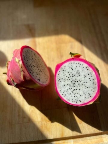 Two halves of a dragon fruit on a wooden surface