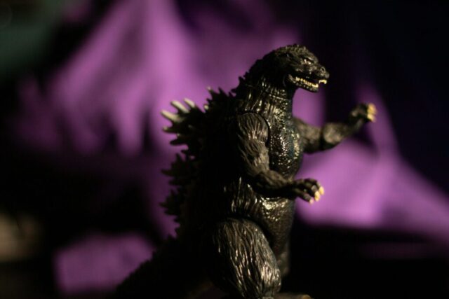 Photo by cocodillaa.com A godzilla toy stands against a purple background