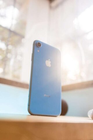 a blue iphone sitting on top of a wooden table