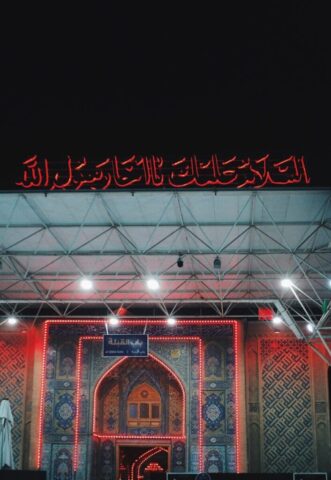 Photo by Cocodillaa.com Islamic calligraphy illuminated with red lights at night.