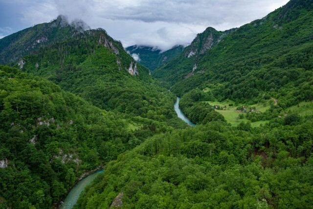Photo by Cocodillaa.com a river running through a valley between mountains with Tara River Canyon in the background
