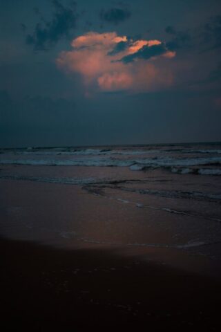 ocean waves crashing on shore during sunset