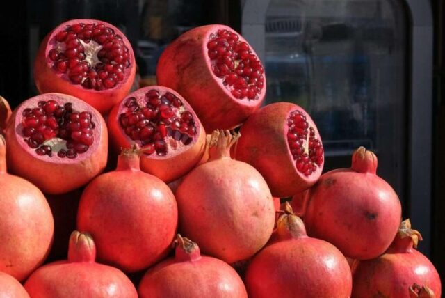 Several ripe pomegranates stacked in a market display.