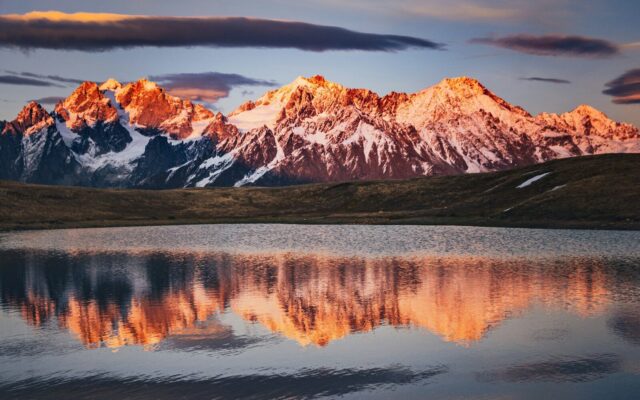 Photo by Cocodillaa.com brown and white mountain near lake under gray sky
