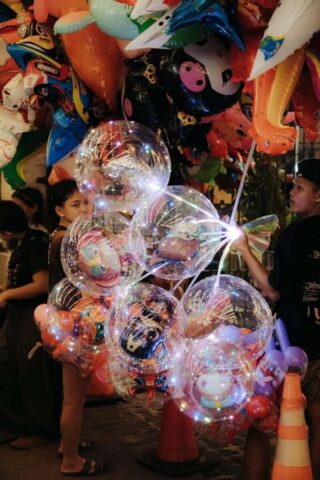 Photo by Cocodillaa.com A vendor holds a bunch of illuminated balloons