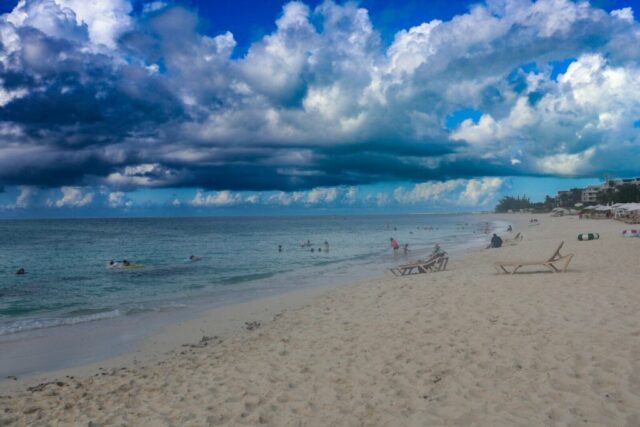 A beach filled with lots of people under a cloudy sky