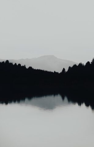 grayscale photography of body of water viewing mountain