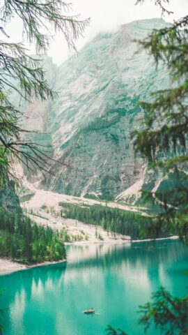 Photo by Cocodillaa.com a boat floating on top of a lake surrounded by mountains