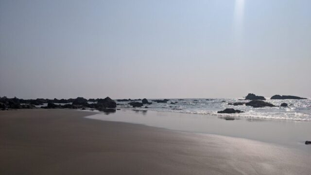 a beach with rocks and water on a sunny day