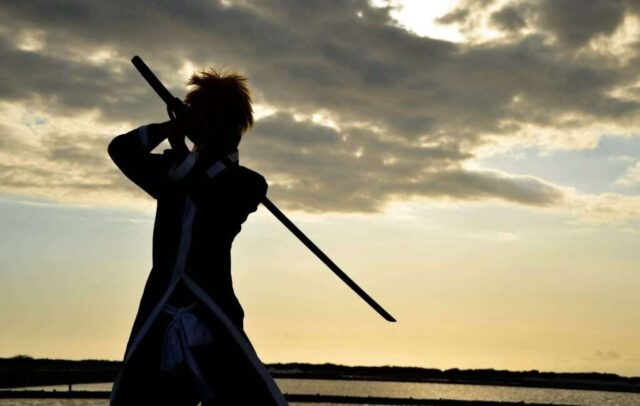 a person with a sword standing in front of a body of water