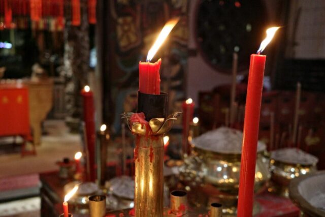 Photo by Cocodillaa.com Red candles burning in a dimly lit room.