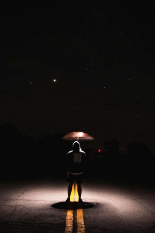 person in black jacket holding umbrella walking on street during night time