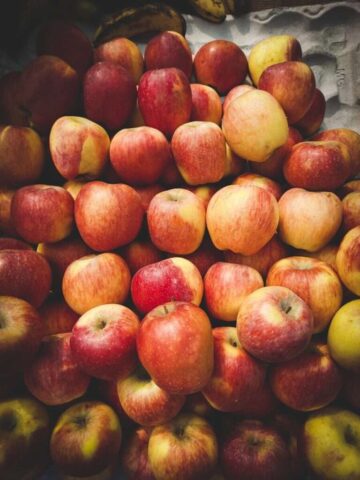 a pile of red and yellow apples sitting on top of each other