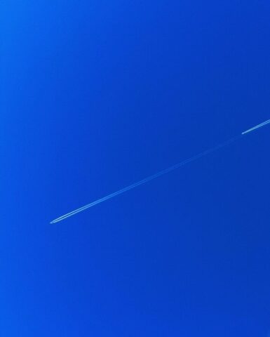 Photo by Cocodillaa.com a jet flying through a blue sky with a contrail