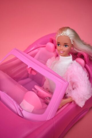 A barbie doll sitting in a pink car