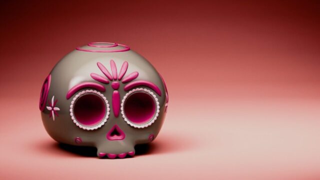 Photo by Cocodillaa.com A decorated sugar skull rests against a red background.
