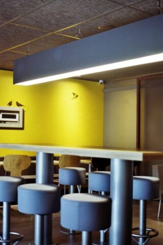 A modern bar area with stools and a yellow wall.