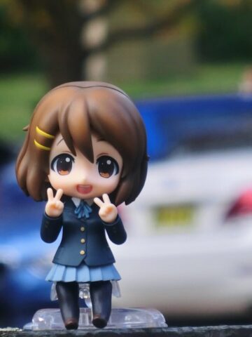 Cute anime figure posing outside with peace signs.