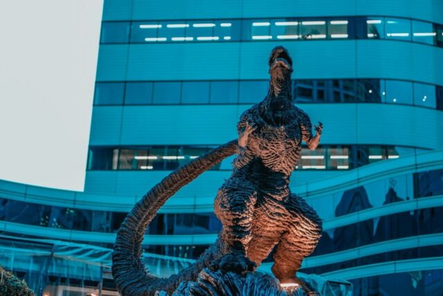 Photo by cocodillaa.com Godzilla stands proudly in front of a building.