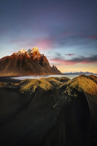 Photo by Cocodillaa.com a mountain with snow on it and grass in the foreground