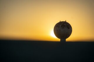 Photo by Cocodillaa.com the sun is setting behind a globe on top of a pole