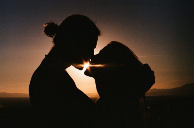 Photo by Cocodillaa.com a man and a woman kissing in front of a sunset