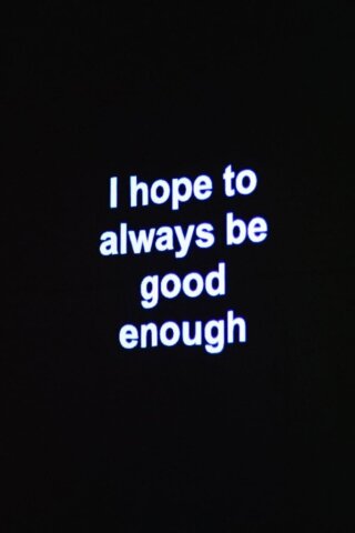 Minimalist motivational quote in neon typography projected in darkness.
