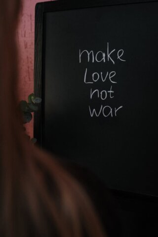 Close-up of a chalkboard with handwritten message 'make love not war', conveying a message of peace.