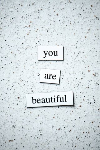 Motivational words 'you are beautiful' on a speckled granite background.
