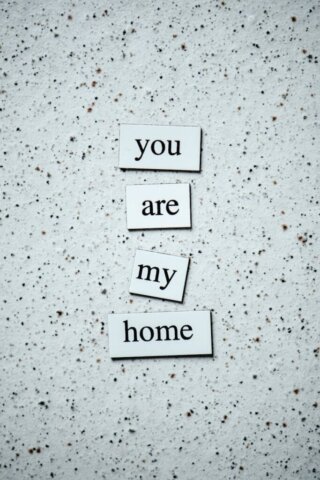 Inspirational phrase 'you are my home' on a speckled surface in black and white format.