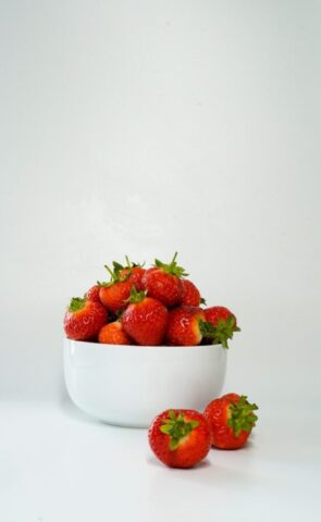 a white bowl filled with lots of ripe strawberries