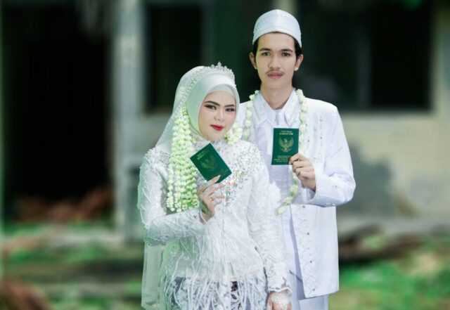 Newlyweds holding marriage books in traditional attire